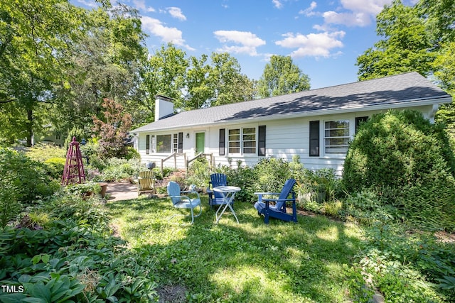 view of front of home with roof with shingles, a chimney, and a front lawn