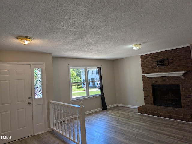 interior space featuring baseboards, a textured ceiling, and wood finished floors