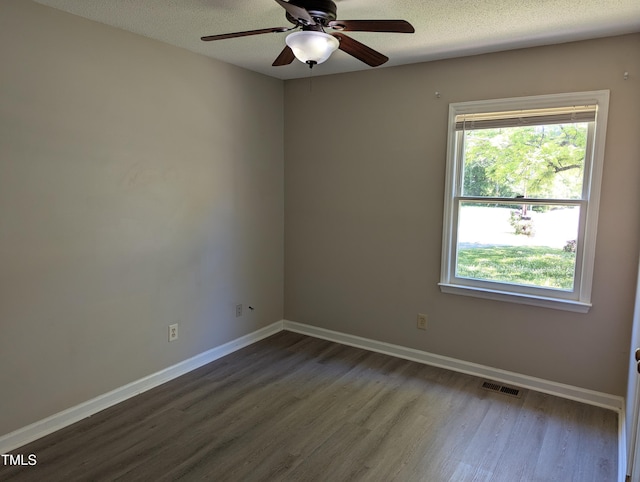 empty room with a ceiling fan, baseboards, visible vents, and dark wood-type flooring