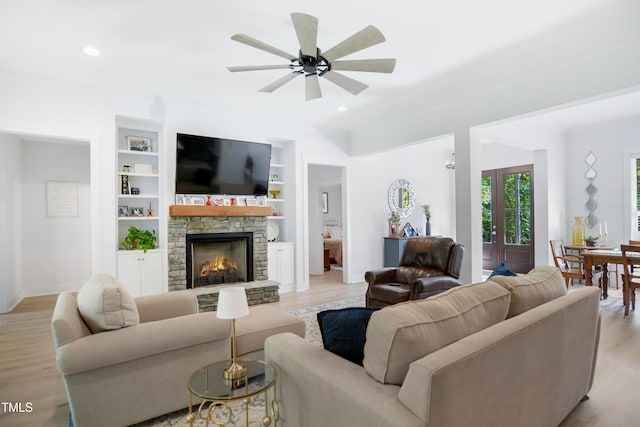 living room with a stone fireplace, a ceiling fan, recessed lighting, and light wood-type flooring