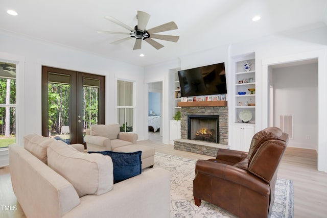 living room with ceiling fan, visible vents, a fireplace, wood finished floors, and ornamental molding