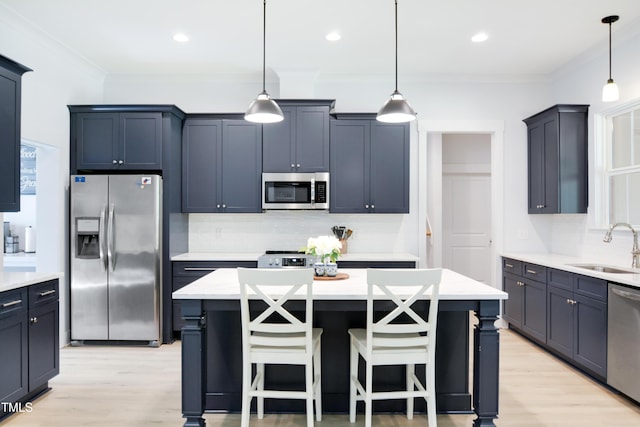 kitchen with a sink, appliances with stainless steel finishes, decorative backsplash, and light wood finished floors