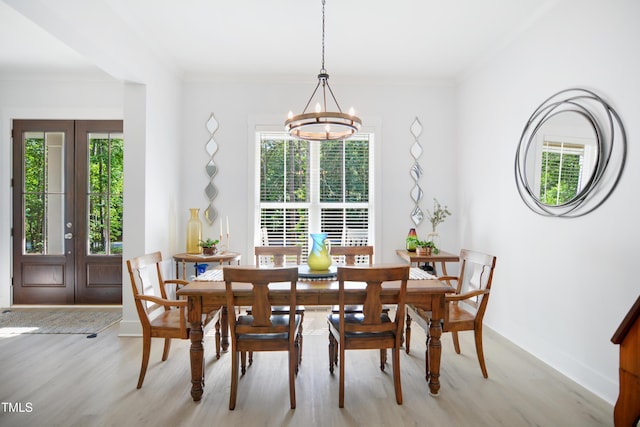 dining area featuring baseboards, ornamental molding, light wood finished floors, and a notable chandelier