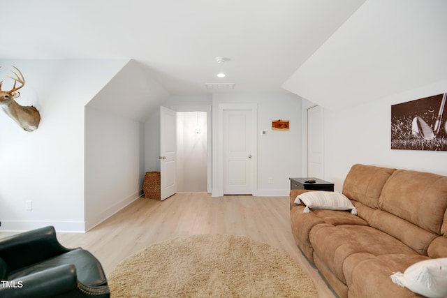 living room featuring light wood-style floors, baseboards, and vaulted ceiling