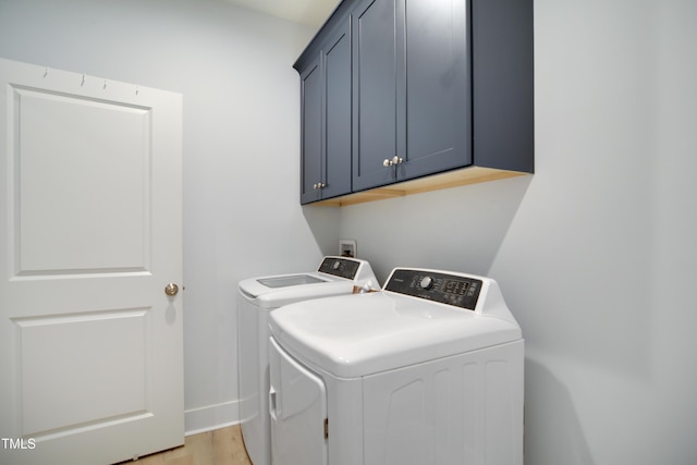 clothes washing area with baseboards, light wood finished floors, cabinet space, and washer and dryer