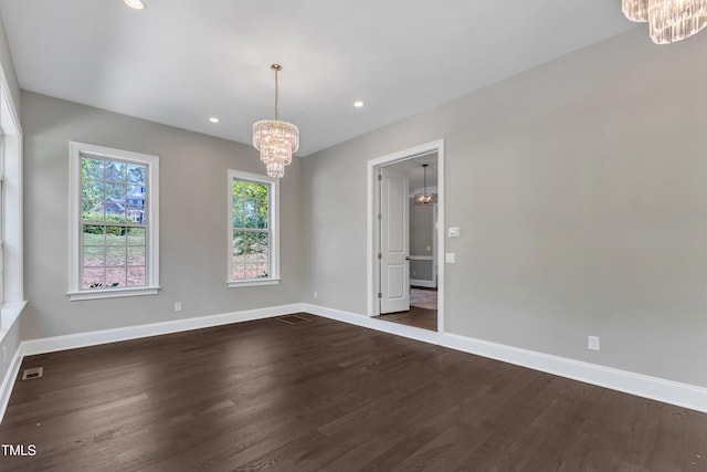 spare room featuring baseboards, dark wood finished floors, and a chandelier