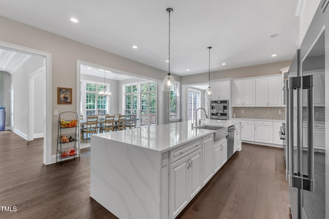 kitchen with stainless steel appliances, dark wood-style floors, a sink, and white cabinetry