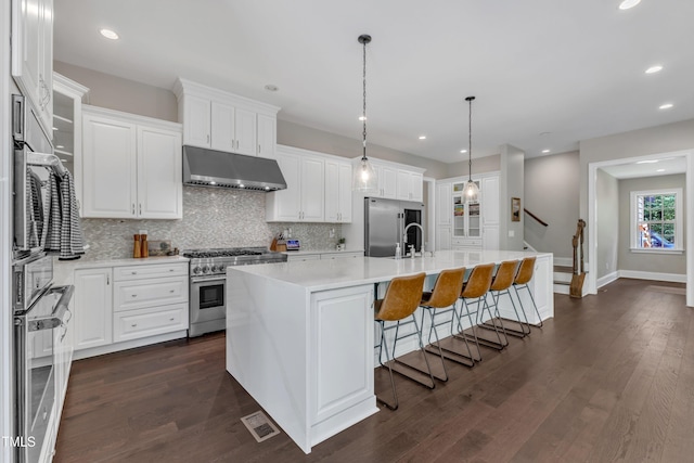 kitchen with decorative backsplash, high quality appliances, light countertops, under cabinet range hood, and white cabinets