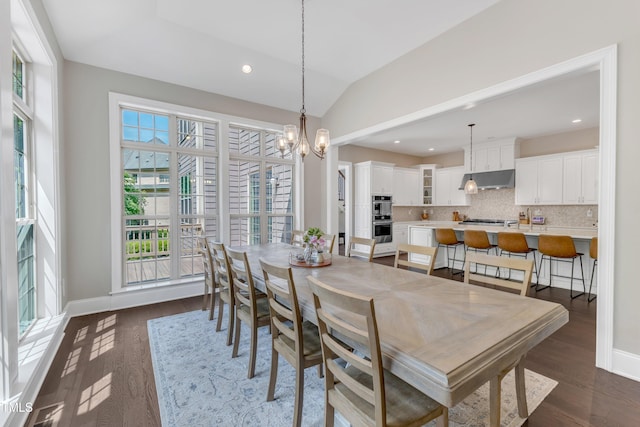 dining room with dark wood-style flooring, a notable chandelier, a healthy amount of sunlight, and vaulted ceiling