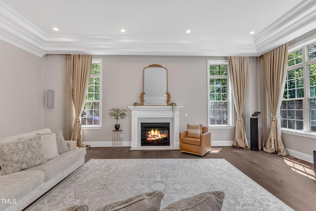 living room with baseboards, ornamental molding, a fireplace with flush hearth, and wood finished floors