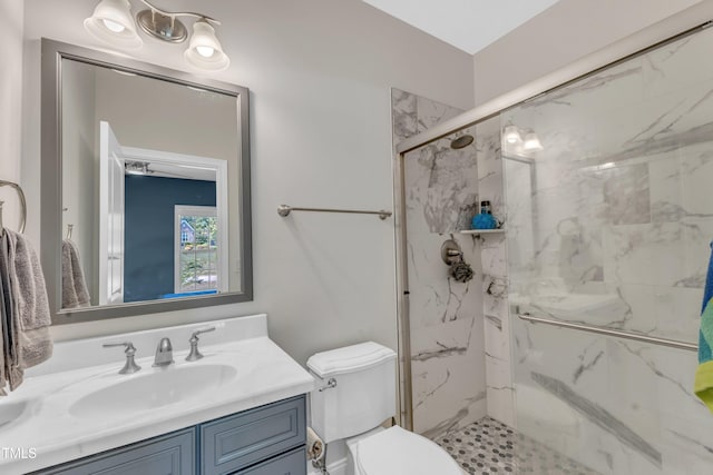 bathroom featuring a marble finish shower, vanity, and toilet