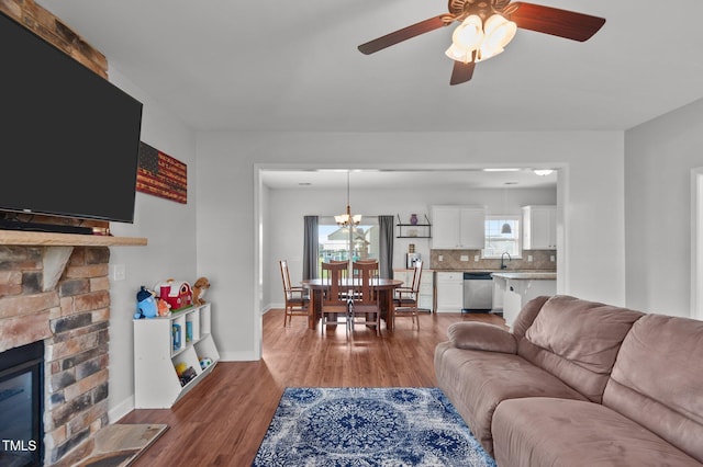 living area featuring baseboards, ceiling fan, wood finished floors, and a fireplace