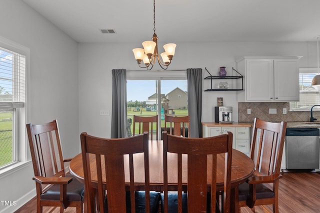 dining room featuring visible vents, a healthy amount of sunlight, a notable chandelier, and dark wood-style floors