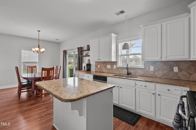 kitchen with white cabinets, a notable chandelier, a sink, tasteful backsplash, and visible vents