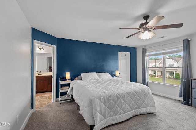 bedroom featuring ceiling fan, light carpet, baseboards, ensuite bathroom, and visible vents