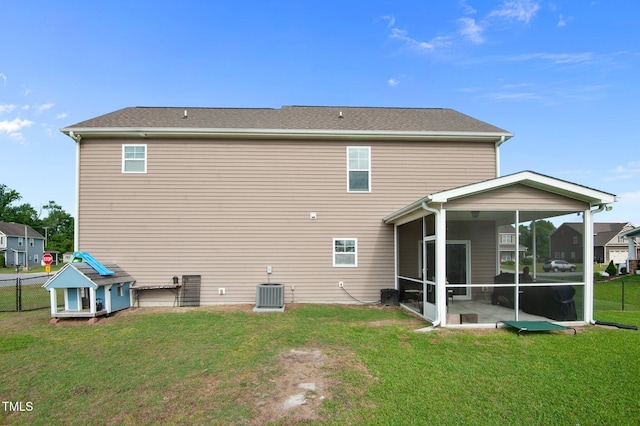 rear view of house with a lawn, fence, and a sunroom