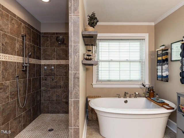 bathroom featuring tile patterned flooring, baseboards, a freestanding tub, ornamental molding, and tiled shower