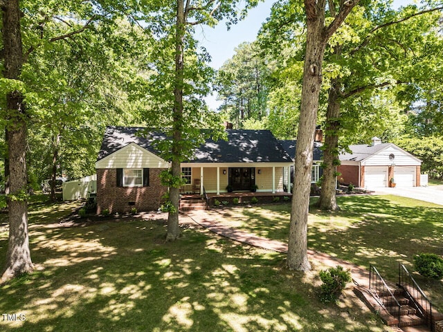 view of front of property with covered porch, a chimney, brick siding, a front lawn, and concrete driveway
