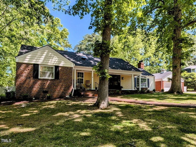 ranch-style house with brick siding, a chimney, a front yard, and a porch