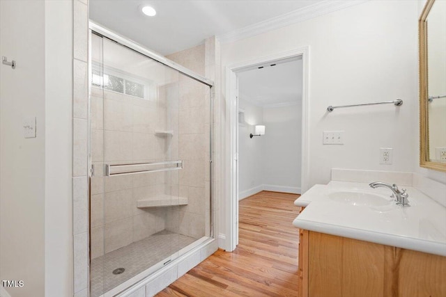 full bathroom featuring ornamental molding, a stall shower, wood finished floors, baseboards, and vanity