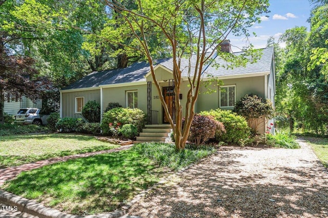 single story home featuring a chimney and a front lawn