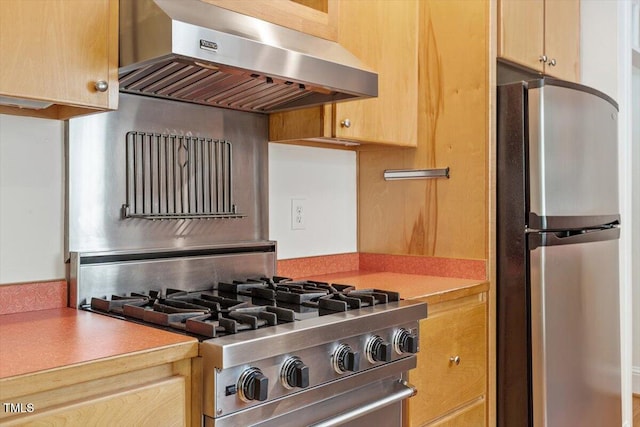 kitchen with exhaust hood, appliances with stainless steel finishes, light countertops, and light brown cabinetry