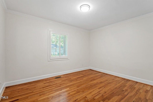 empty room with light wood-style flooring, crown molding, and baseboards