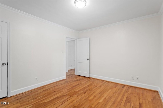 empty room with light wood-type flooring, ornamental molding, and baseboards