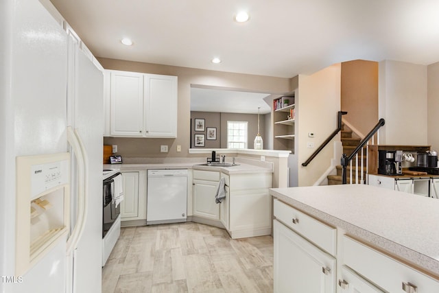 kitchen with a sink, light countertops, white cabinets, and white appliances