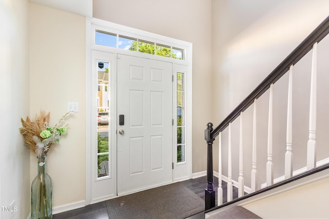 foyer entrance with baseboards, a high ceiling, stairs, and dark wood-type flooring