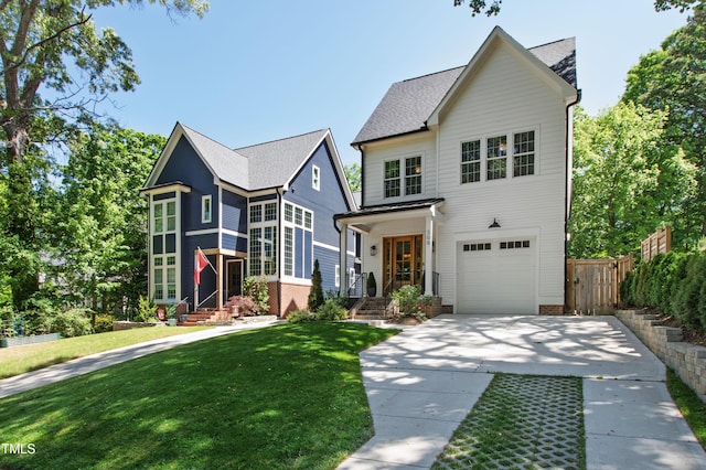 traditional home featuring fence, an attached garage, driveway, and a front yard