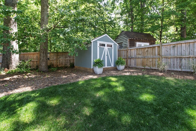 view of yard with an outdoor structure, a fenced backyard, and a shed