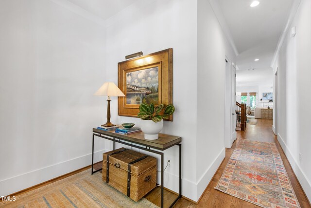 hall featuring baseboards, ornamental molding, wood finished floors, and recessed lighting