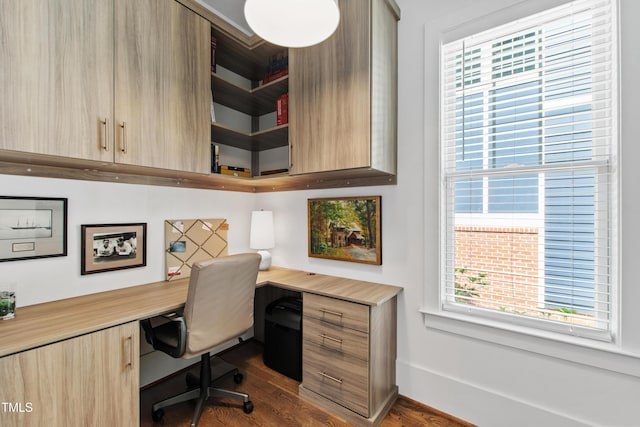 office area with built in study area, baseboards, and dark wood-type flooring