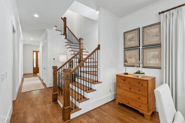 staircase featuring recessed lighting, baseboards, ornamental molding, and wood finished floors