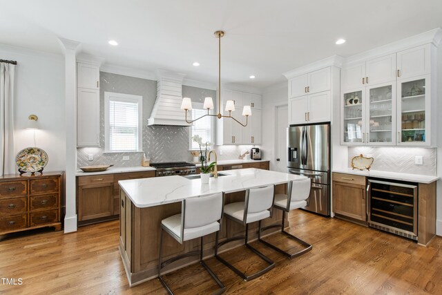 kitchen featuring beverage cooler, range, a chandelier, custom range hood, and stainless steel refrigerator with ice dispenser