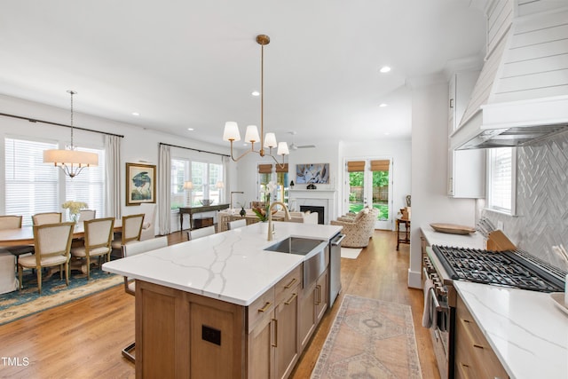 kitchen with a chandelier, open floor plan, appliances with stainless steel finishes, and premium range hood