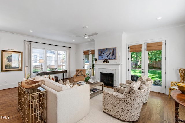 living area featuring ornamental molding, ceiling fan, wood finished floors, and a fireplace