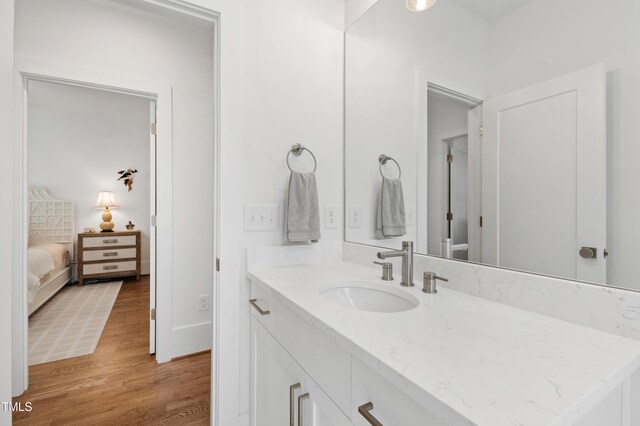 ensuite bathroom with vanity, connected bathroom, and wood finished floors