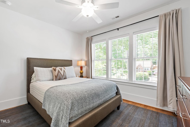 bedroom featuring visible vents, baseboards, dark wood-style flooring, and ceiling fan