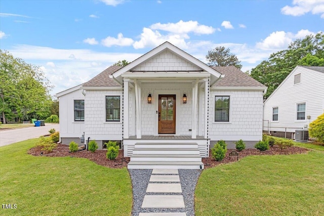 bungalow-style house featuring a porch, a shingled roof, central AC, and a front yard