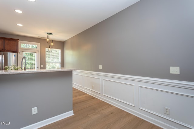 8719 Cypress Grove Run, Raleigh, NC 27612 - kitchen with freestanding refrigerator, wainscoting, recessed lighting, light wood-style flooring, and decorative light fixtures