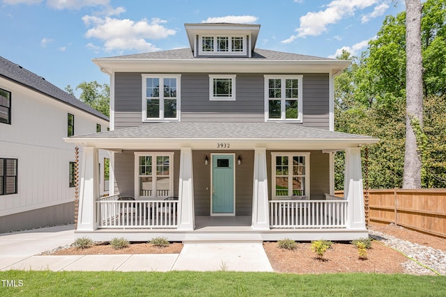 traditional style home with fence, a shingled roof, and a porch