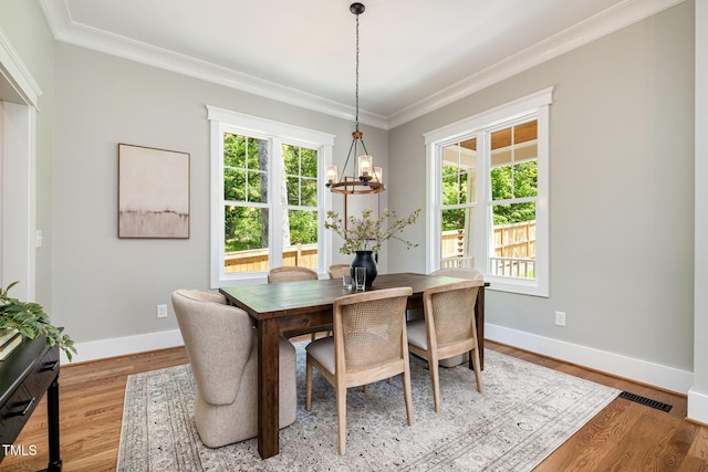dining room with crown molding, baseboards, an inviting chandelier, and visible vents