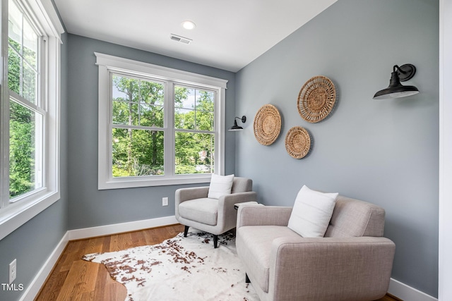 living area with plenty of natural light, baseboards, wood finished floors, and visible vents