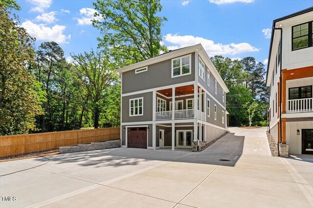 3932 Old Chapel Hill Rd, Durham, NC 27707 - rear view of house featuring an attached garage, french doors, fence, concrete driveway, and a balcony