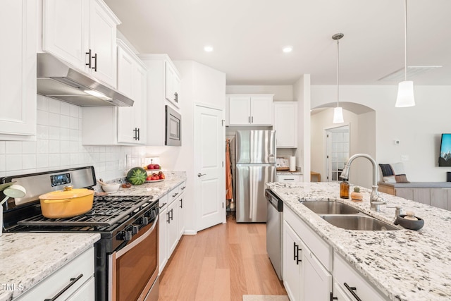 2404 Azalea Dr, Durham, NC 27703 - kitchen featuring appliances with stainless steel finishes, under cabinet range hood, a sink, arched walkways, and light wood finished floors