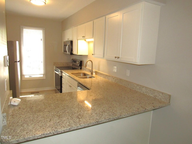 kitchen with light stone countertops, baseboards, white cabinetry, a sink, and appliances with stainless steel finishes