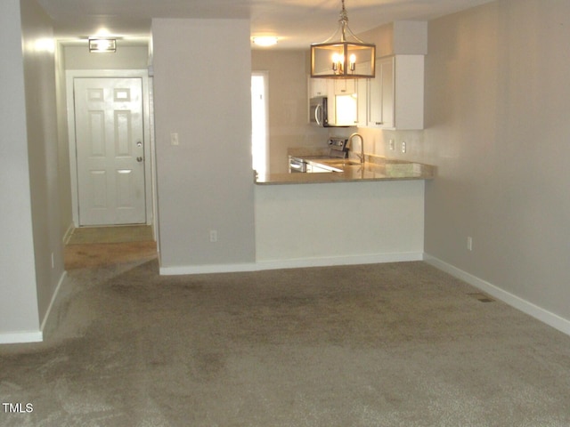 kitchen with pendant lighting, baseboards, a sink, carpet, and appliances with stainless steel finishes