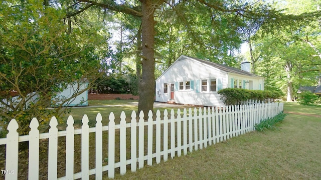view of home's exterior with a chimney, a yard, and fence private yard